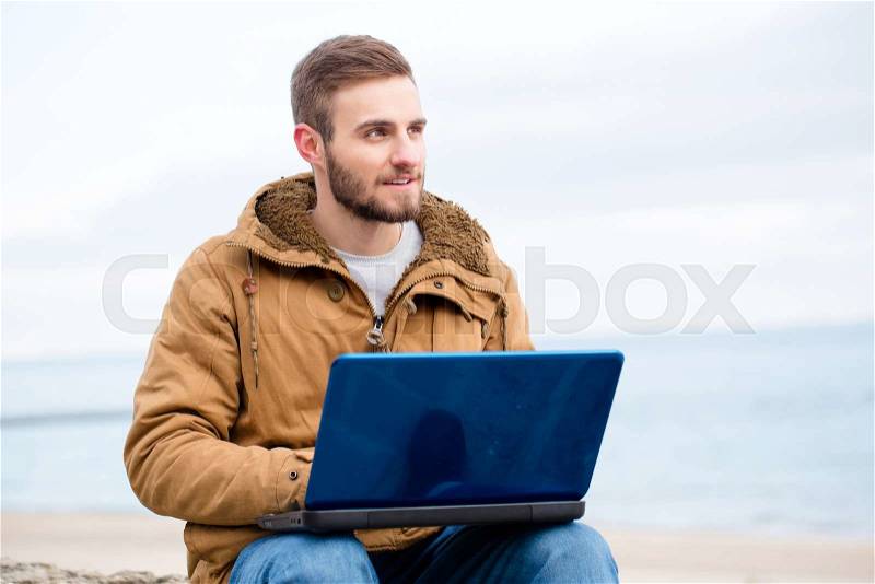 Portrait of a handsome man using laptop computer outdoors, stock photo