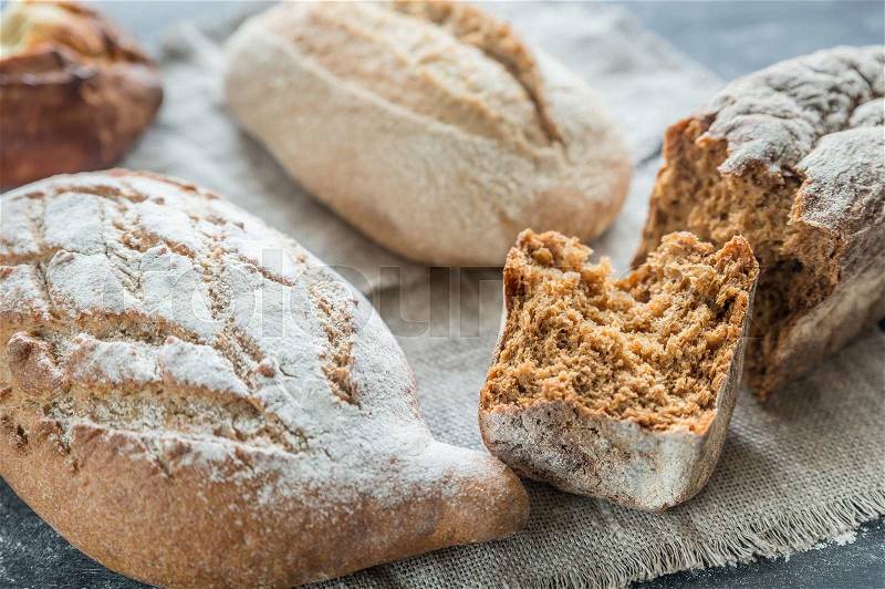 Whole grain breads on the dark wooden background, stock photo
