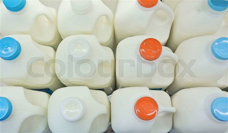 Milk bottles on fridge shelf in supermarket store, stock photo