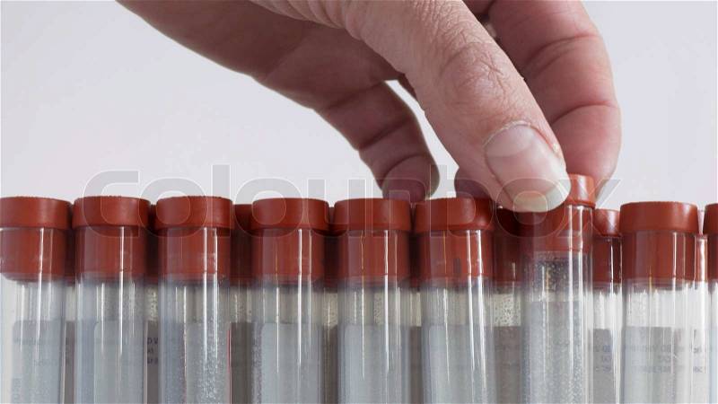 Woman takes a blood collecting tube from a row of tubes, stock photo