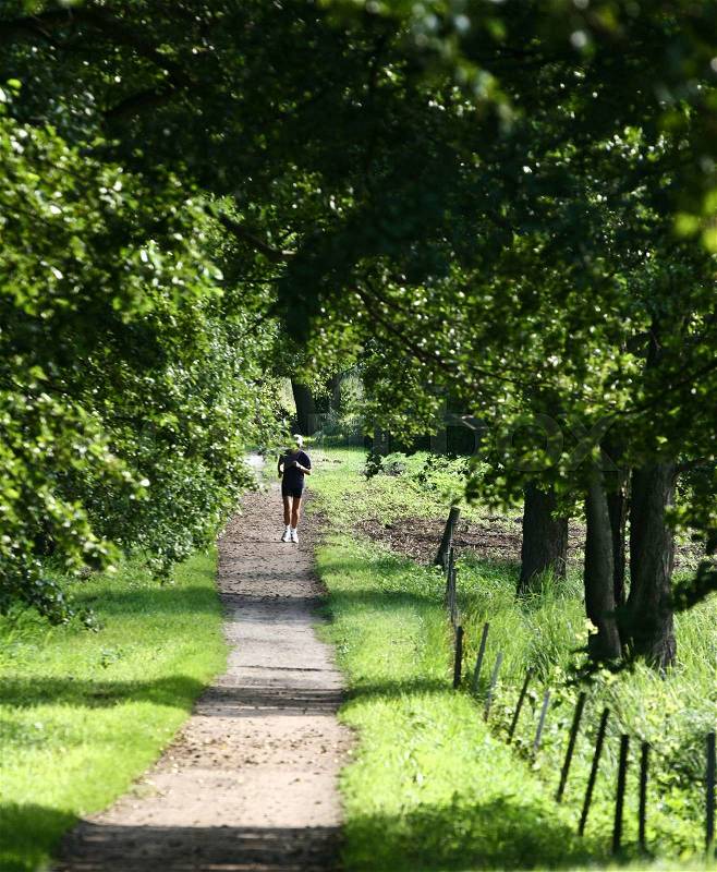 Man running jogging on a forest path. His head is behind a tree branch, stock photo