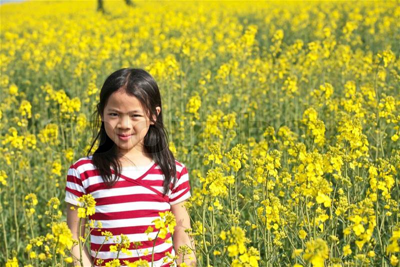 Young girl in a rapse field in the summer in the countryside in denmark, stock photo