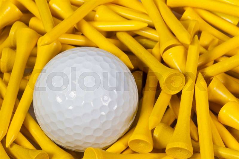 White golf ball lying between yellow wooden golf tees, stock photo