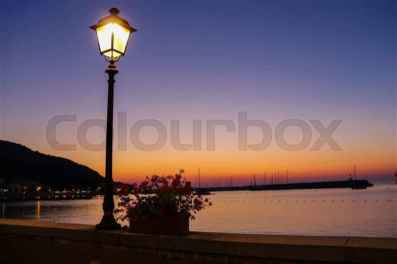 Lighted lantern on coast of the Tyrrhenian Sea on the sunset. Elba Island, Italy, stock photo