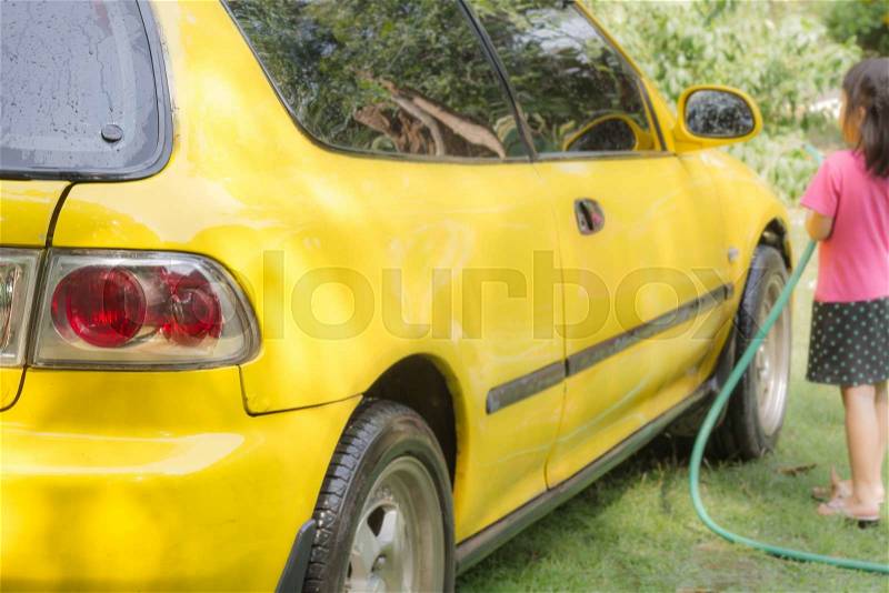 Washing Car, Little asian kid girl washing old yellow car on the grass, stock photo