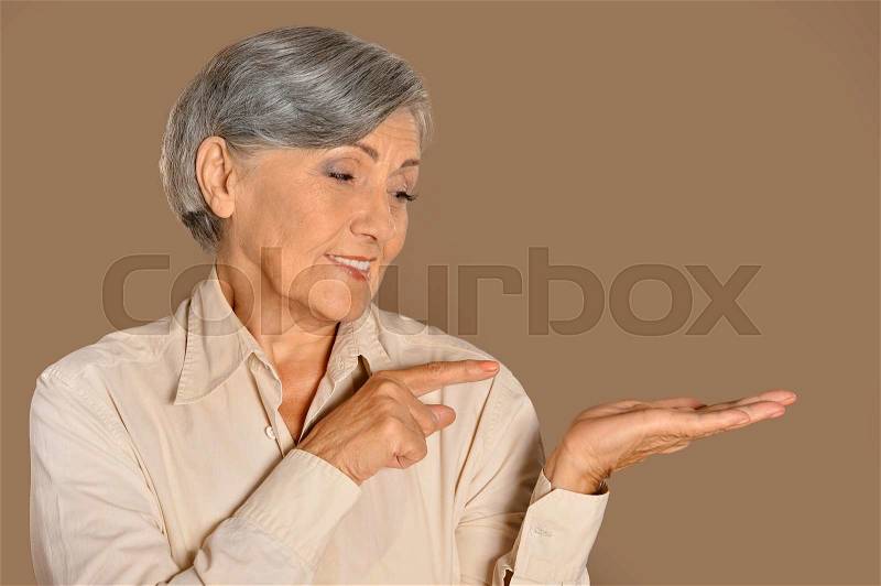 Portrait of senior woman pointing by her finger, stock photo