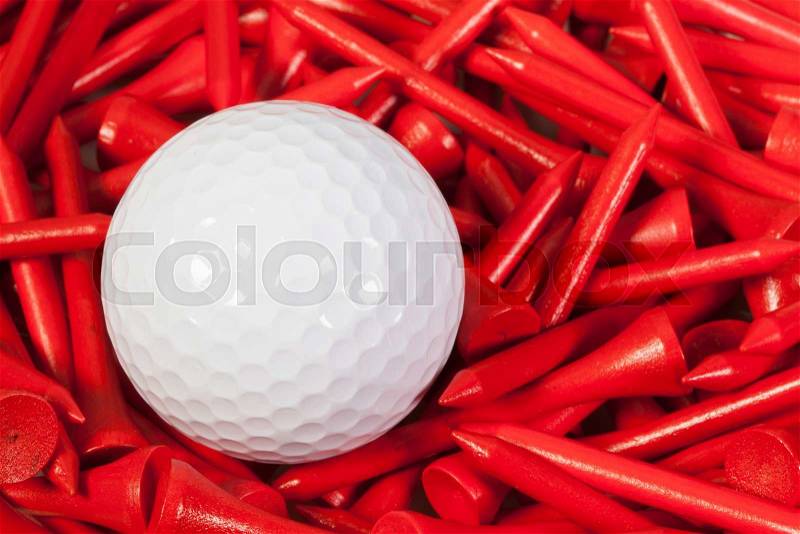 White golf ball lying between red wooden golf tees, stock photo