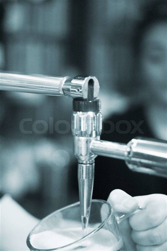 Lager draft beer pump and barman pulling pint of beer into glass in British pub bar wedding party reception in England, stock photo