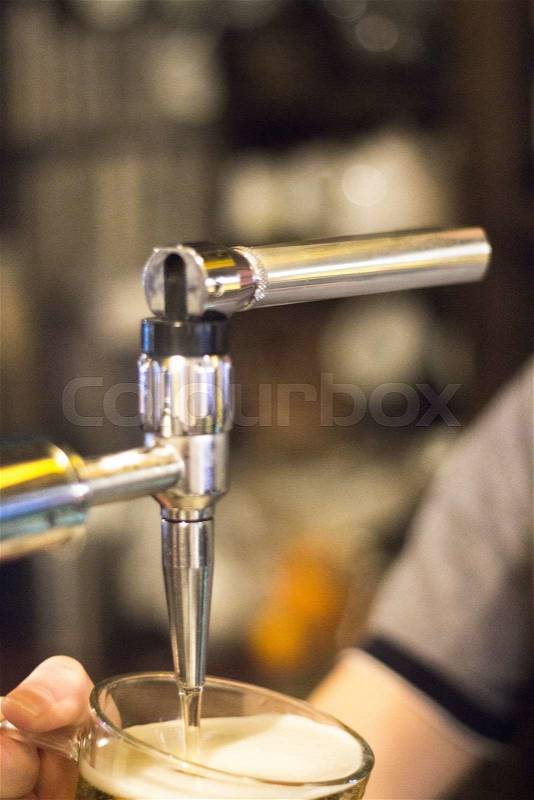 Lager draft beer pump and barman pulling pint of beer into glass in British pub bar wedding party reception in England, stock photo