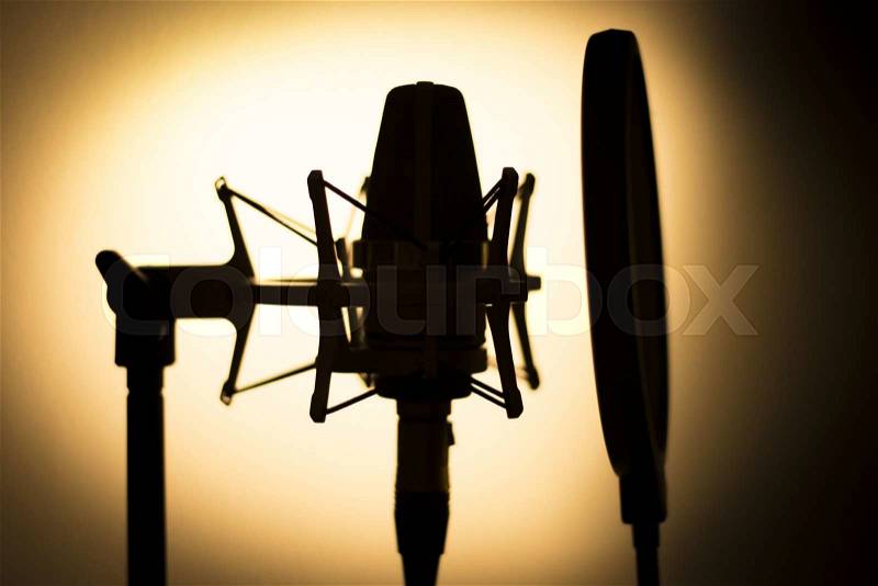 Audio recording vocal studio voice microphone silhouette with anti shock mount and built in anti pop filter for singing and voiceover actors doing voiceovers, stock photo