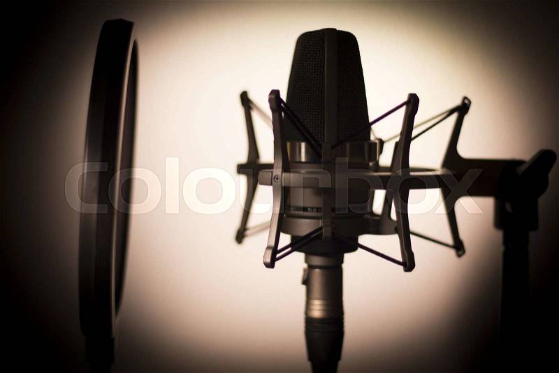 Audio recording vocal studio voice microphone silhouette with anti shock mount and built in anti pop filter for singing and voiceover actors doing voiceovers, stock photo