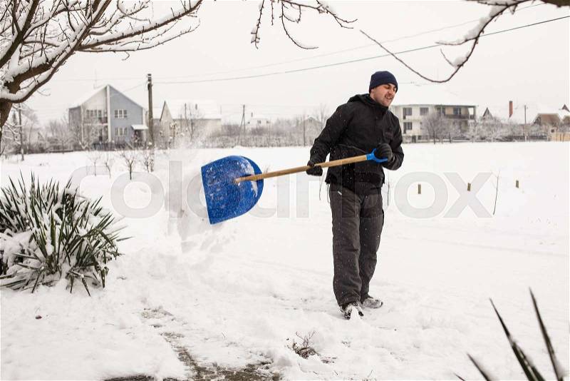 Young man remove snow near the suburban house, stock photo