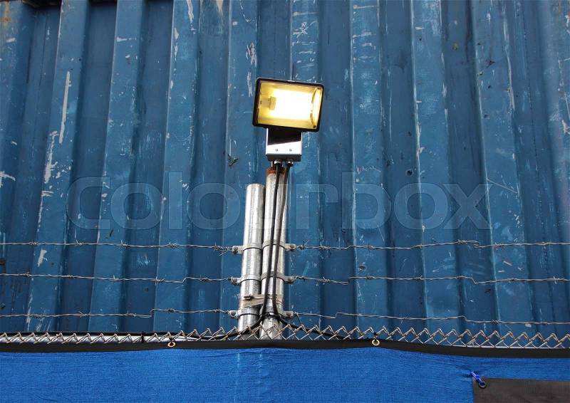 Surveillance Search Light on Blue Metal Background with Barbwire, stock photo