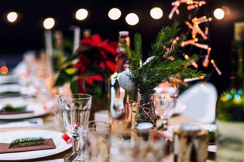Decorated Christmas holiday table ready for dinner. Beautifully decorated table set with candles, spruce twigs, plates and serviettes for event in the restaurant, stock photo