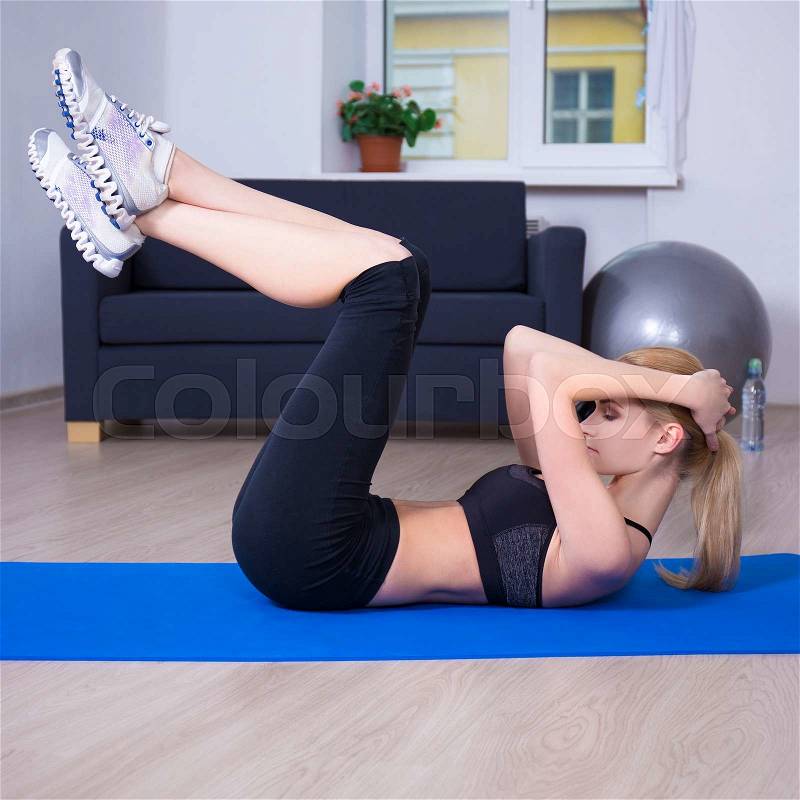 Slim woman doing exercises for abdominal muscles at home, stock photo