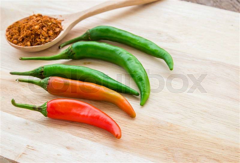 Chili powder and fresh chili on cutting board on wooden table background, stock photo