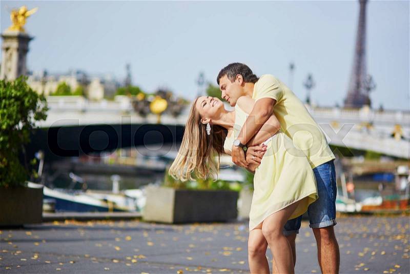 Romantic dating couple of tourist in Paris, kissing near the famous Alexandre III bridge over the Seine, stock photo