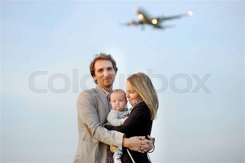 Young family portrait with airplane on background, stock photo