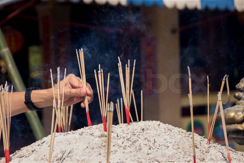 Hand placing incense sticks in the pot, stock photo