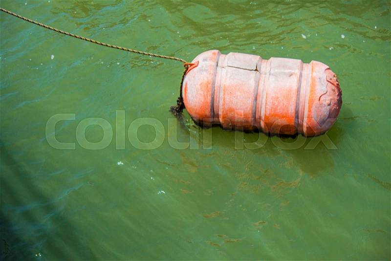 The orange buoy floating on the green color water, stock photo