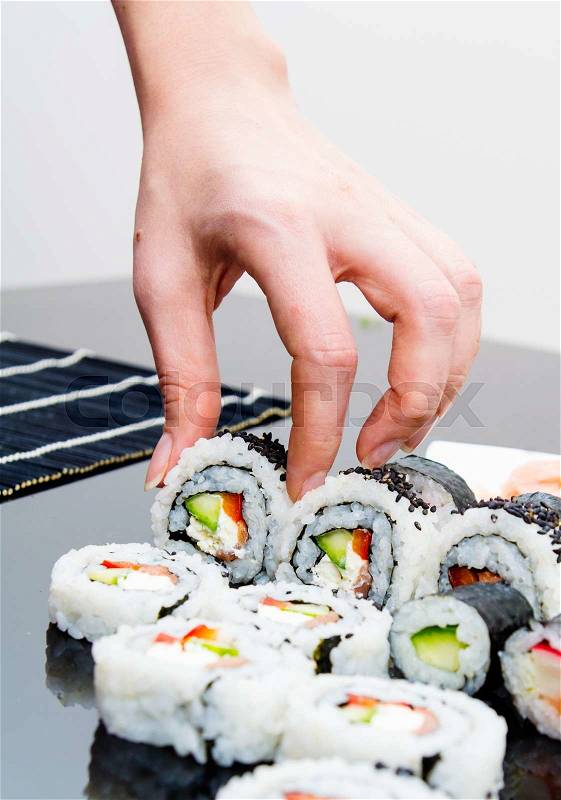 Hand holding sushi on black background, stock photo