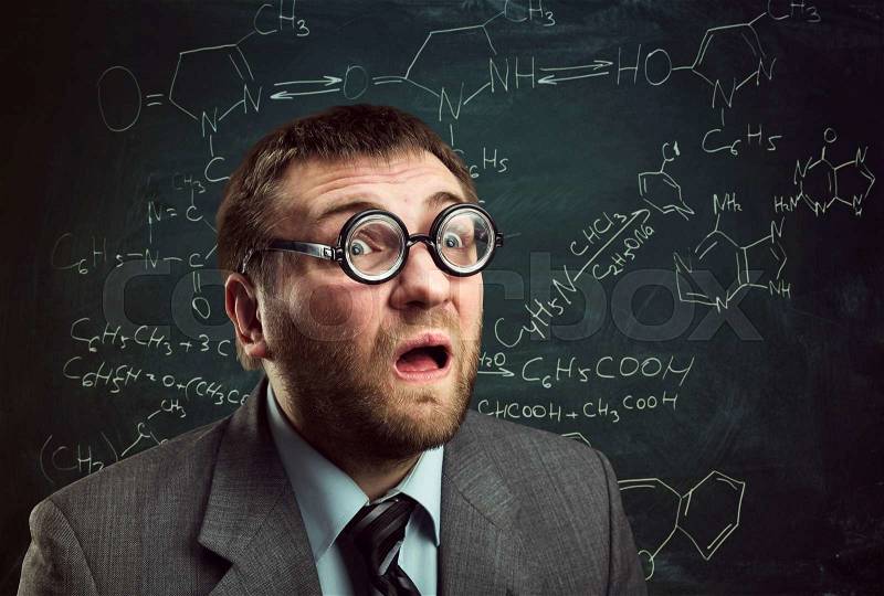 Bizarre professor in glasses thinking over chemical formulas on blackboard, stock photo