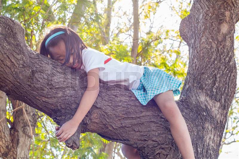 Close up asian children climbing trees are afraid of falling trees, stock photo