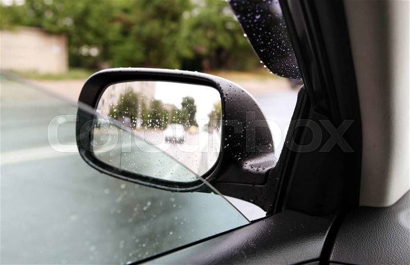 Car driving on empty road, rear-view mirror in rainy weather, stock photo