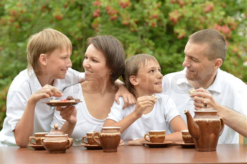 Happy family drinking tea in summer garden, stock photo