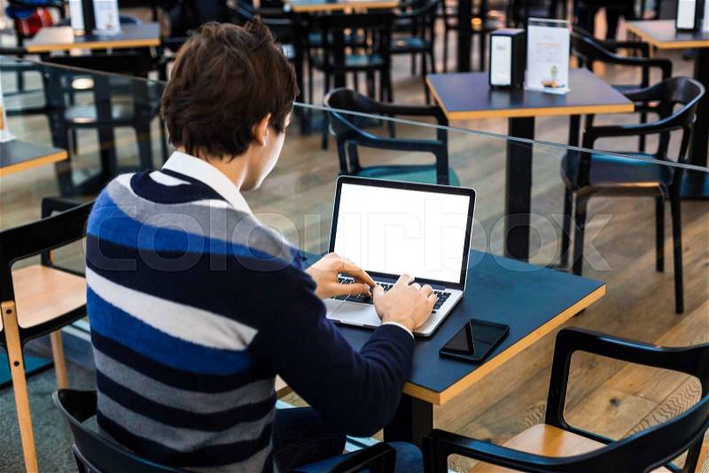 Closeup picture of man is typing on a laptop. Business freelance man sitting at a wooden table in airport or terminal cafe. His laptop is in front of him, stock photo