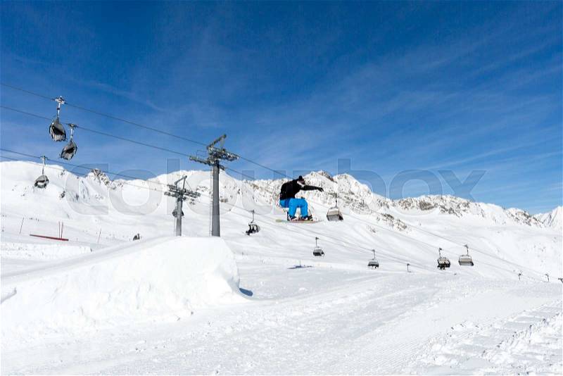 Male snowboarder performs a jumping trick at the snowpark in Soelden, Austria, stock photo