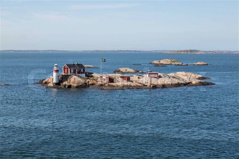 Gaveskar lighthouse in the archipelago of Gothenburg with a hoisted Swedish flag and a typical Swedish Red Cottage, stock photo