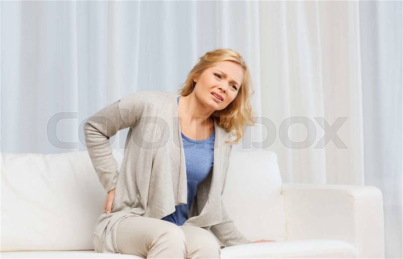 People, healthcare and problem concept - unhappy woman suffering from pain in back or reins at home, stock photo
