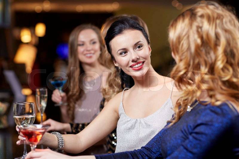Celebration, friends, bachelorette party and holidays concept - happy women drinking champagne and cocktails at night club, stock photo