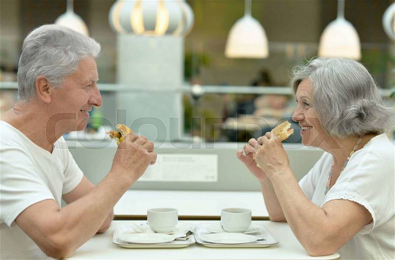 Portrait of beautiful elderly couple eating fast food, stock photo