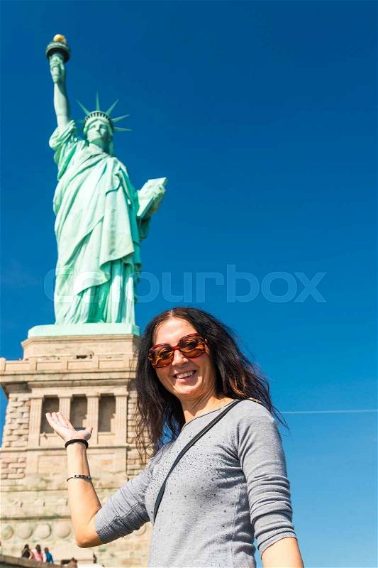 Happy woman joking at the base of Statue of Liberty, New York, stock photo