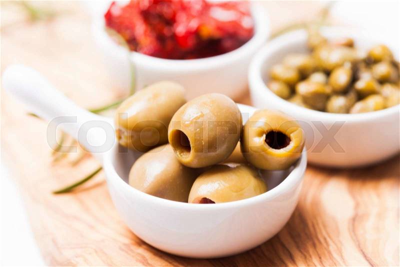 Marinated olives - in a white saucer on a board, stock photo