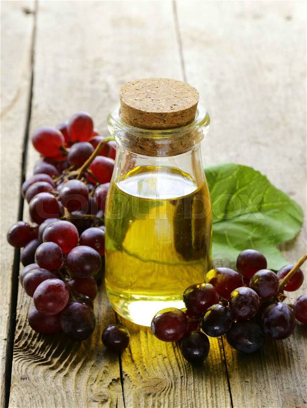 Bottle with grape seed oil on a wooden table, stock photo