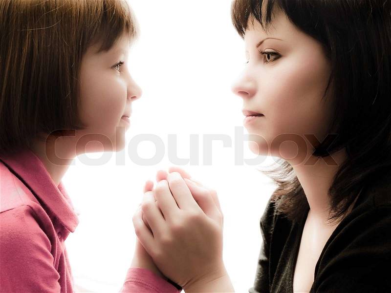 Mother and daughter sitting opposite each other, watch each other\'s eyes and hold hands, stock photo