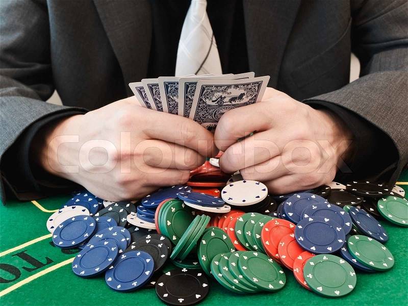 Man plays cards at the casino, and keeps the card in the hands of top-won chips, stock photo