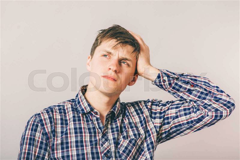 Young guy thinks his hand on his temple, stock photo