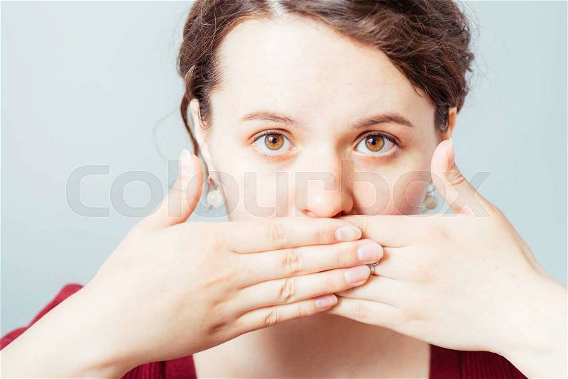 Woman closes the mouth with her hands, stock photo