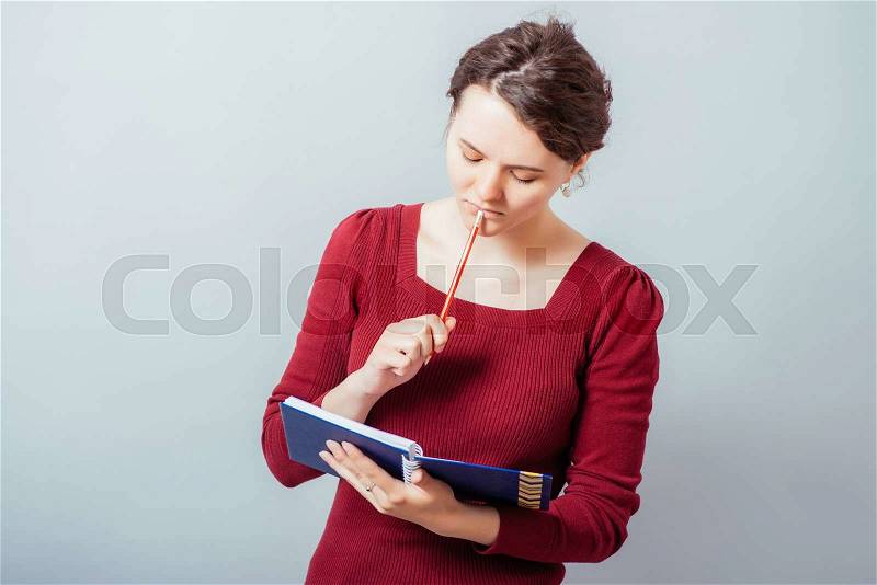 Happy young woman writes something to the workbook, stock photo