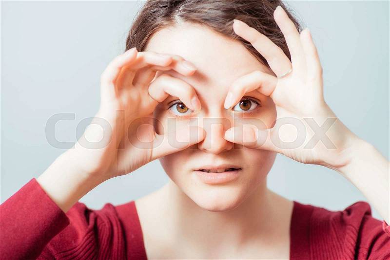 Woman with hands makes binoculars, stock photo