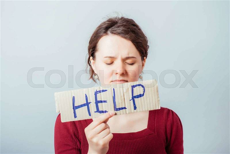 Woman with the word Help on kraft cardboard. On a gray background, stock photo