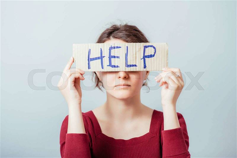 Woman with the word Help on kraft cardboard. On a gray background, stock photo