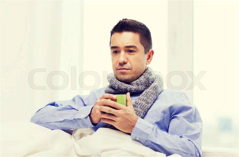Healthcare, people and medicine concept - ill man with flu drinking hot tea from cup at home, stock photo