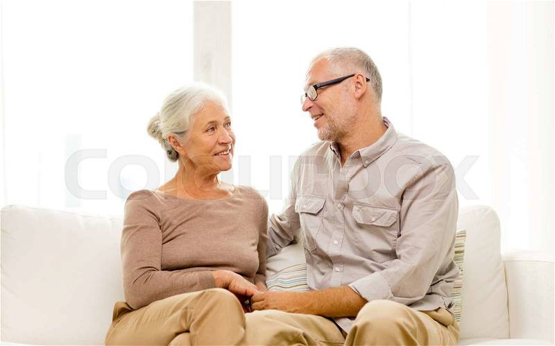 Family, holidays, age and people concept - happy senior couple sitting on sofa at home, stock photo