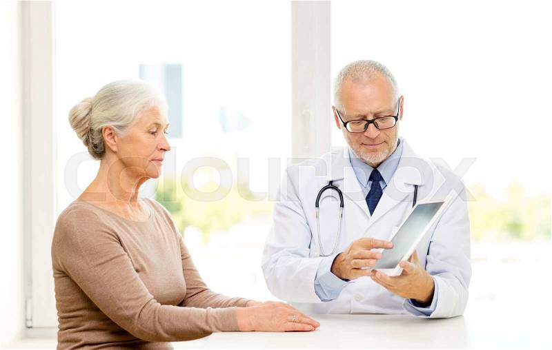 Medicine, age, health care and people concept - senior woman and doctor with tablet pc computer meeting in medical office, stock photo