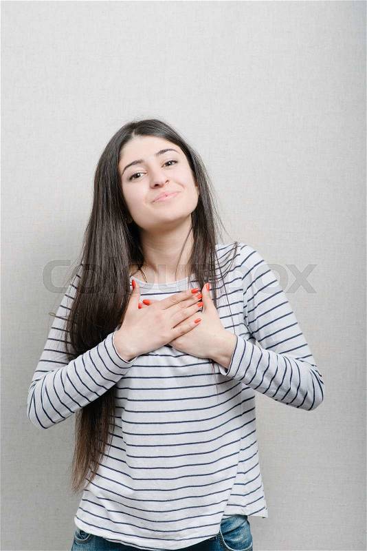 Woman hands over his chest, his heart. On a gray background, stock photo